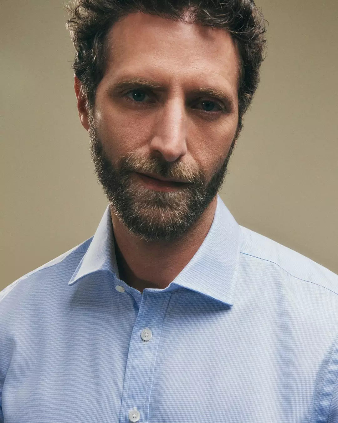 Man wearing a light blue shirt against a beige background